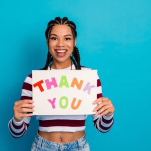 Young,Woman,With,Colorful,Thank,You,Sign,Smiles,At,The